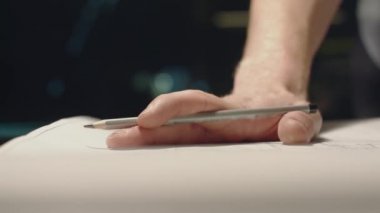 Genç adam geceleri ofiste çalışıyor. Elinde kalem tutma, çizimgörüntüleme.