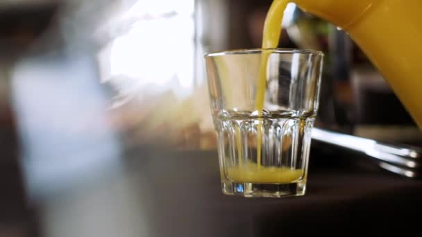 Апельсиновый сок наливают в пустой стакан из кувшина . — стоковое видео