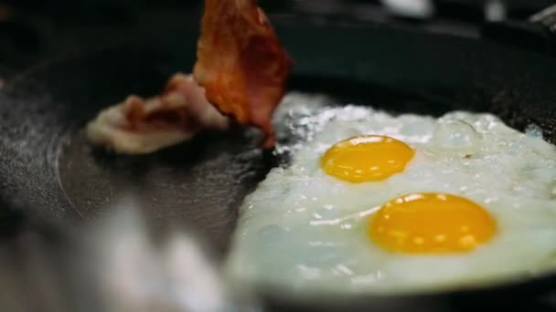 Kochen köstliche Spiegeleier mit Speck in der Pfanne. — Stockvideo