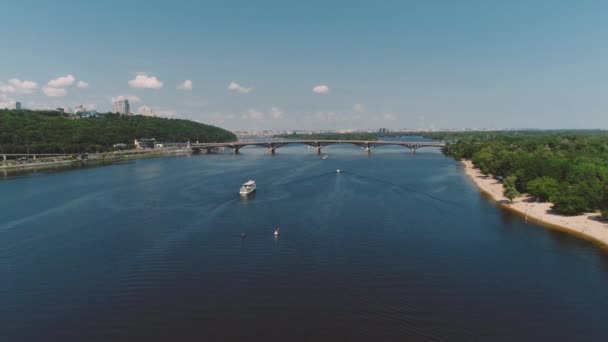 Vitt kryssningsfartyg flyter längs floden nära vackra moderna bron. — Stockvideo