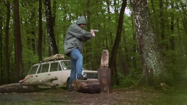 Slow Motion av casual Strong man arbetar med AX i vilda lövskog och Vintage klassisk bil i bakgrunden. — Stockvideo