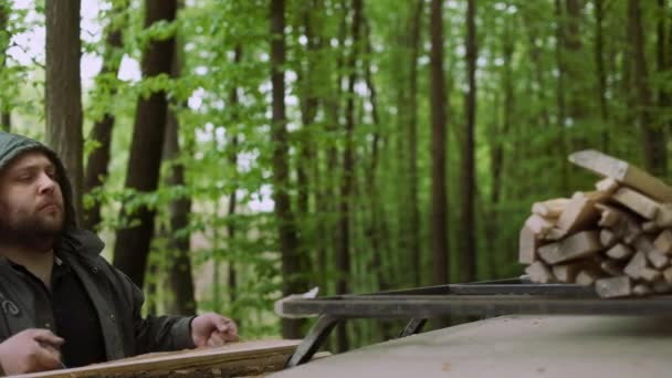 Le mouvement lent de l'homme fort occasionnel travaille avec le bois de chauffage près de la voiture dans la forêt décidue sauvage . — Video