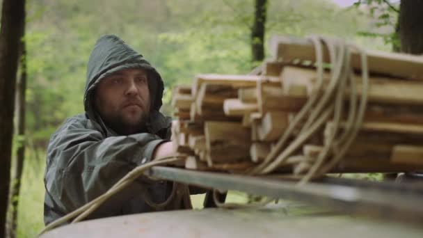 Pomalý pohyb příležitostného silného muže pracuje se dřevem a provazem poblíž auta v divokém opadavých lesích. — Stock video