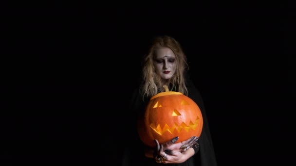 Imagem de Halloween. Bruxa jovem em roupas pretas segura abóbora em suas mãos . — Vídeo de Stock