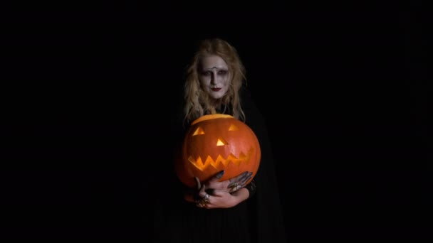 Halloween-Bild: junge Hexe in schwarzen Kleidern hält Kürbis in den Händen. — Stockvideo