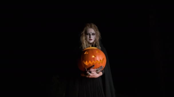 Halloween-Bild: junge Hexe in schwarzen Kleidern hält Kürbis in den Händen. — Stockvideo