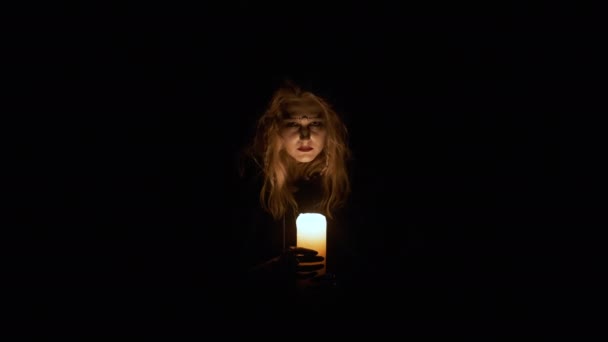 Halloween bilden. Porträtt av den unga häxan. Häxan håller ljus i sina händer. — Stockvideo
