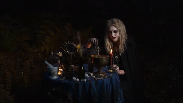 Halloween Afbeelding. Jonge heks bereidt magische drank in kommen. — Stockvideo
