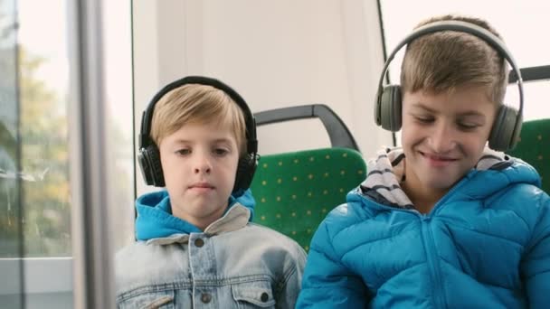 Zwei Jungen auf dem Beifahrersitz im Bus spielen Smartphones. — Stockvideo