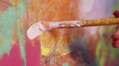 Fırçayla sanatçı kızların eli. Tuvale resim yaparken yumuşak hareketler yapıyor..