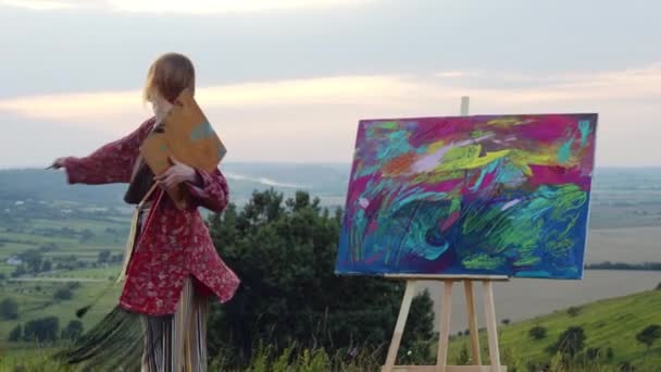 Jeune artiste dansant dans la nature près de la peinture. — Video