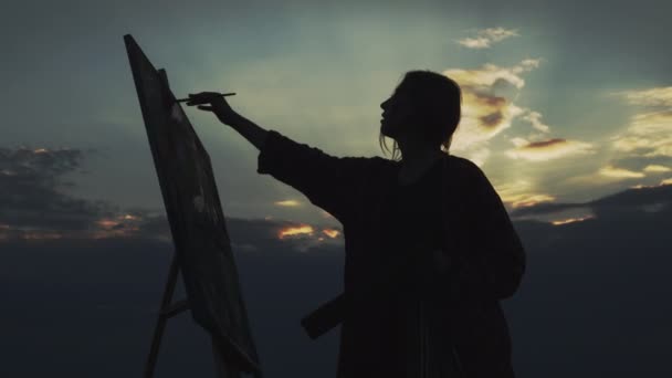 Chica artista pinta cuadro en la naturaleza al atardecer. — Vídeos de Stock