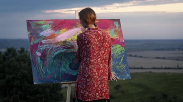 Fille artiste peint tableau avec ses mains trempées dans la peinture. — Video