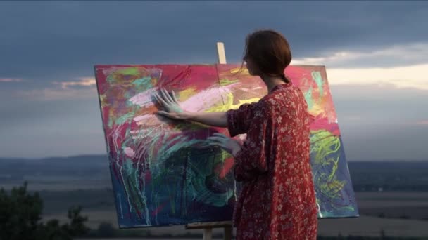 彼女の手で絵を描く少女アーティストは、ペイントに浸しました.彼女の手で絵に描いた. — ストック動画