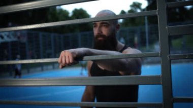 Spor sahasındaki genç adam spor yaparken dinleniyor..