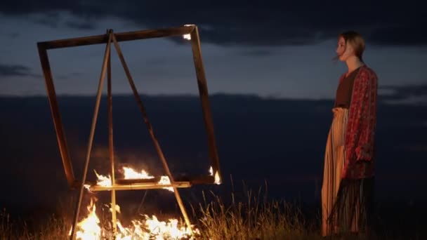 年轻的女艺术家站在大自然中的黄昏中，站在一只燃烧着图画的鳗鱼面前. — 图库视频影像