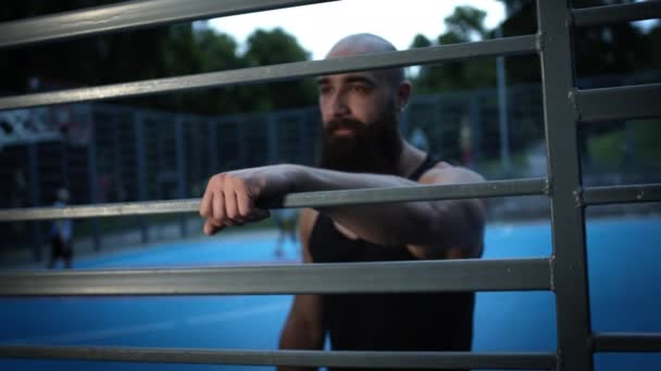 Jovem no campo de esportes descansando durante os esportes. — Vídeo de Stock