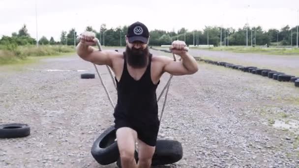 Athletic Guy Goes In For Sports. Man Runs And Pulls Car Tires Tied To A Rope. Front View. — Stock Video
