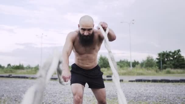 El atlético se mete en deportes. El hombre sostiene cuerdas en sus manos y las mueve. — Vídeo de stock