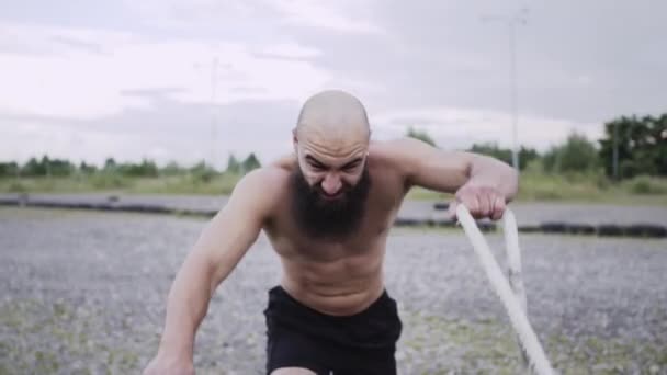 Atletisk kille går in för sport. Människan håller rep i sina händer och flyttar dem. — Stockvideo