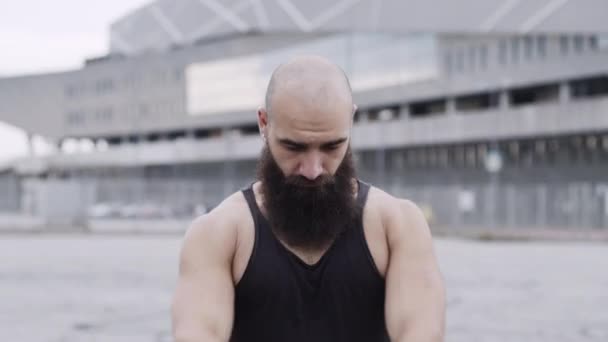 Sportowiec trenuje na ulicy. Facet z brodą sprawia, że ruchy dłoni. — Wideo stockowe