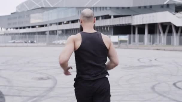 スポーツフィギュアを持つスポーティ男が通りを走っている. — ストック動画