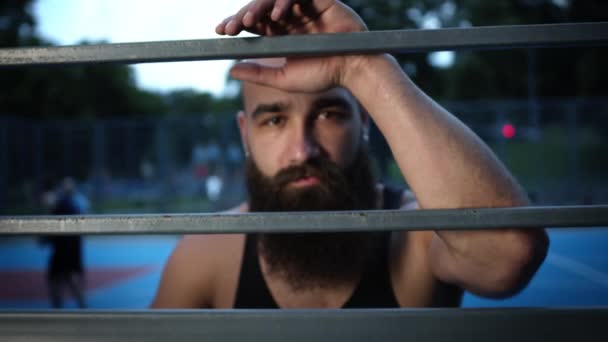 Jovem no campo de esportes descansando durante os esportes. — Vídeo de Stock