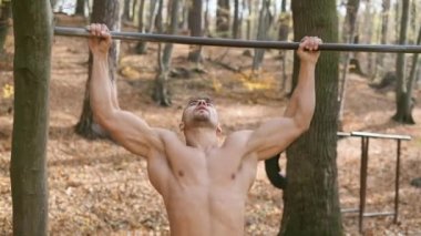 Güçlü Çıplak Adam Direk 'te duruyor. Egzersiz, erkeğin tüm kaslarını vurgular.