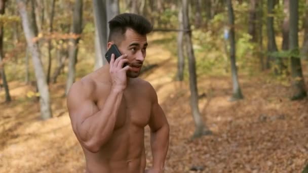 秋の公園に裸のトルソと強い男は立ち、携帯電話で話します — ストック動画