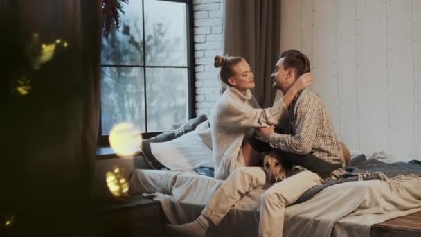 Nouvel An. Jeune couple dans un appartement confortable. Couple et leur chien au lit. — Video