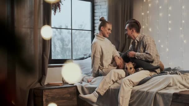 Nowy Rok. Młoda para w przytulnym mieszkaniu. Para i ich pies w łóżku. — Wideo stockowe