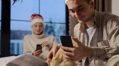 Yeni yıl. Noel Baba Şapkalı genç çift yeni yıl arifesinde evlerinde köpekleriyle.