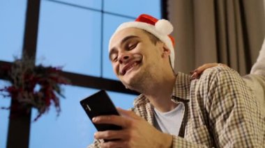 Yeni yıl. Cep telefonlu Noel Baba Şapkalı Genç Çift.