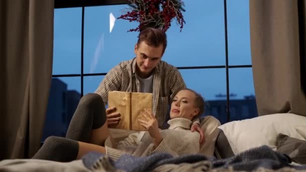Año Nuevo. Joven pareja lectura libro en la cama. — Vídeos de Stock