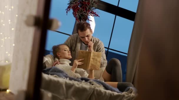 Neujahr. Junges Paar liest Buch im Bett. — Stockvideo