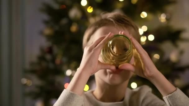 Новий рік. Смішний хлопчик сидить за столом. Він п'є сік . — стокове відео