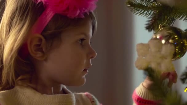 Nieuwjaar. Meisje spelen kerstboom decoratie opknoping op kerstboom. — Stockvideo