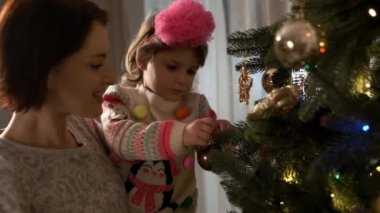 Yeni yıl. Anne ve küçük kızı Noel ağacını süslüyor..