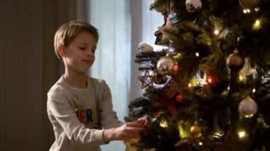 Yeni yıl. Komik çocuk Noel ağacını süslüyor.