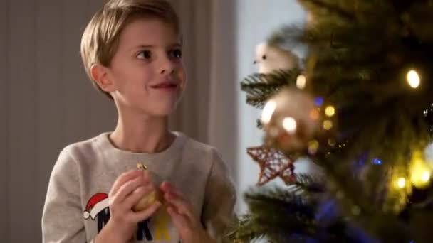 Πρωτοχρονιά. Αστείο αγόρι διακοσμεί το χριστουγεννιάτικο δέντρο. — Αρχείο Βίντεο