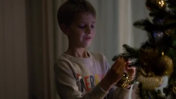 Πρωτοχρονιά. Αγόρι διακοσμεί το χριστουγεννιάτικο δέντρο. — Αρχείο Βίντεο