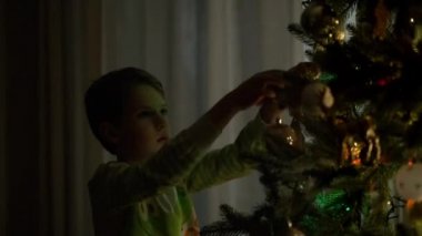 Yeni yıl. Küçük çocuk Noel ağacını süslüyor..