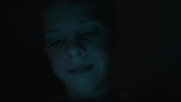 黑暗中男孩的脸在玩桌面上的游戏. — 图库视频影像