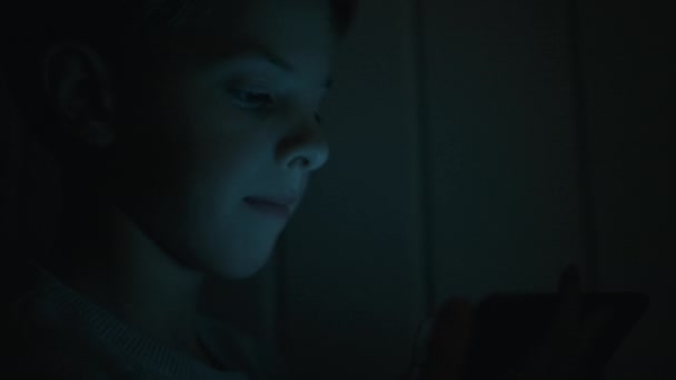 Πρόσωπο του αγοριού στο σκοτάδι Παίζοντας παιχνίδια στο tablet. — Αρχείο Βίντεο