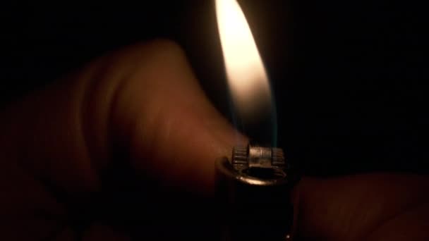 Un briquet brûle dans la main des hommes. La lumière du briquet dans l'obscurité — Video