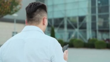 Adam sokakta yürüyor ve cep telefonuyla konuşuyor..