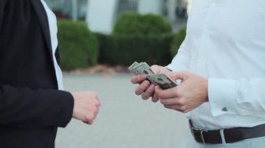 Kadın ve erkeğin elleri. İş adamı parayı sayar ve kıza verir. Anlaşmayı el sıkışıyorlar.