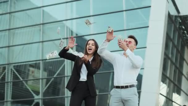 Молодой человек и женщина в деловой одежде разбрасывают деньги по улицам. — стоковое видео
