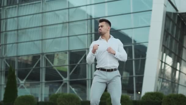 Jeune homme en vêtements d'affaires dansant près d'un immeuble de bureaux — Video