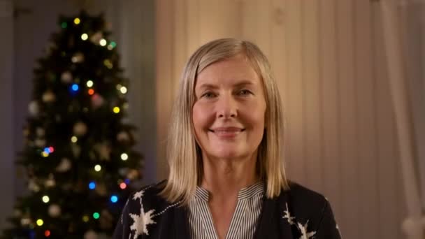 Portrét starší ženy na pozadí vánočního stromu. — Stock video